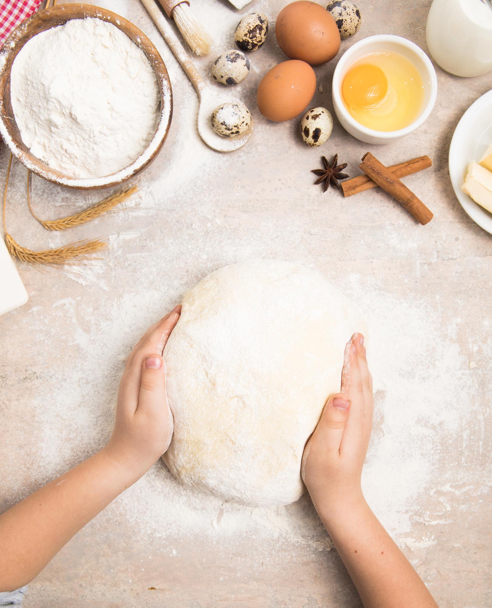 Close-up hands kneading dough on wooden board