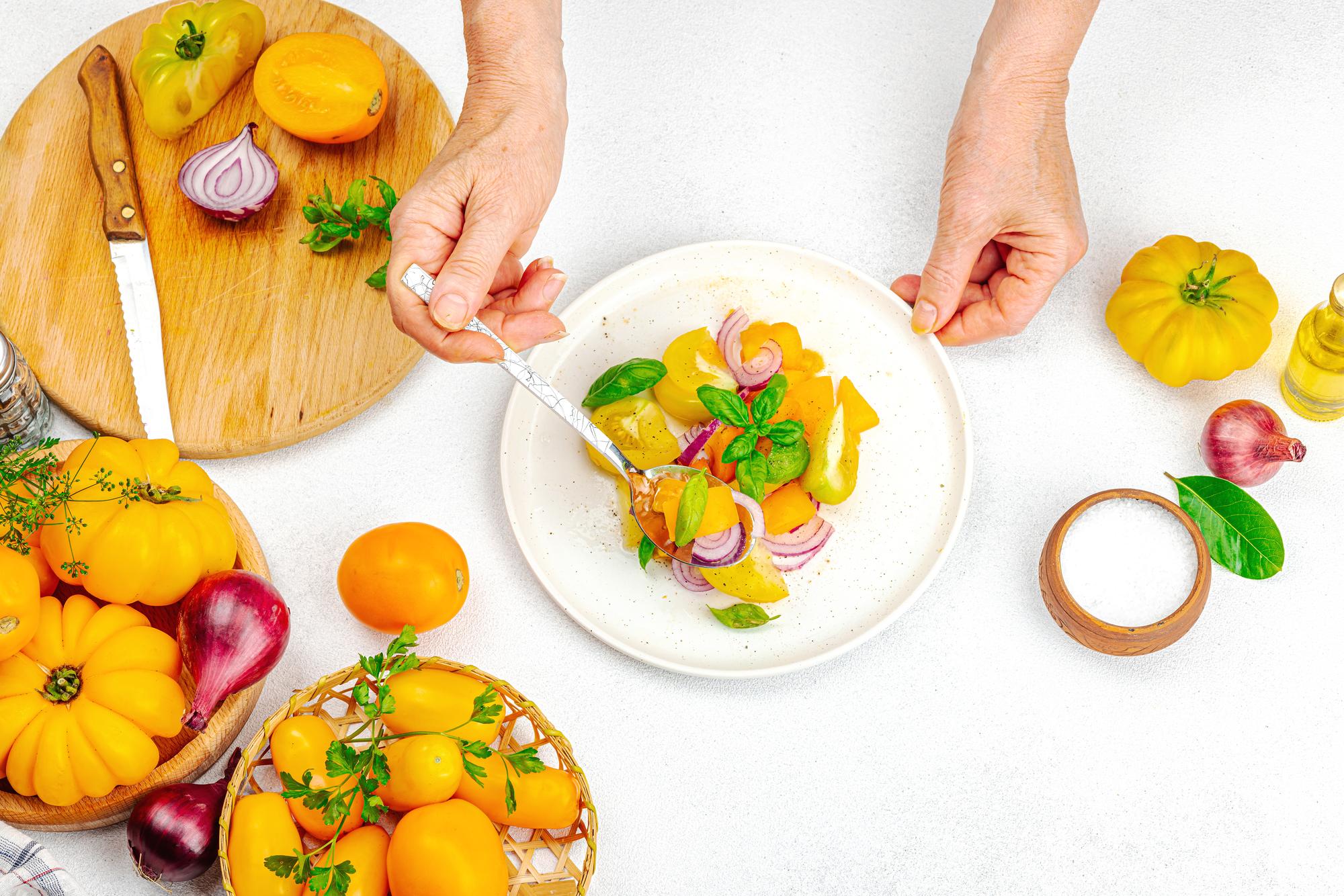 Hands preparing plated seasonal meal in studio kitchen